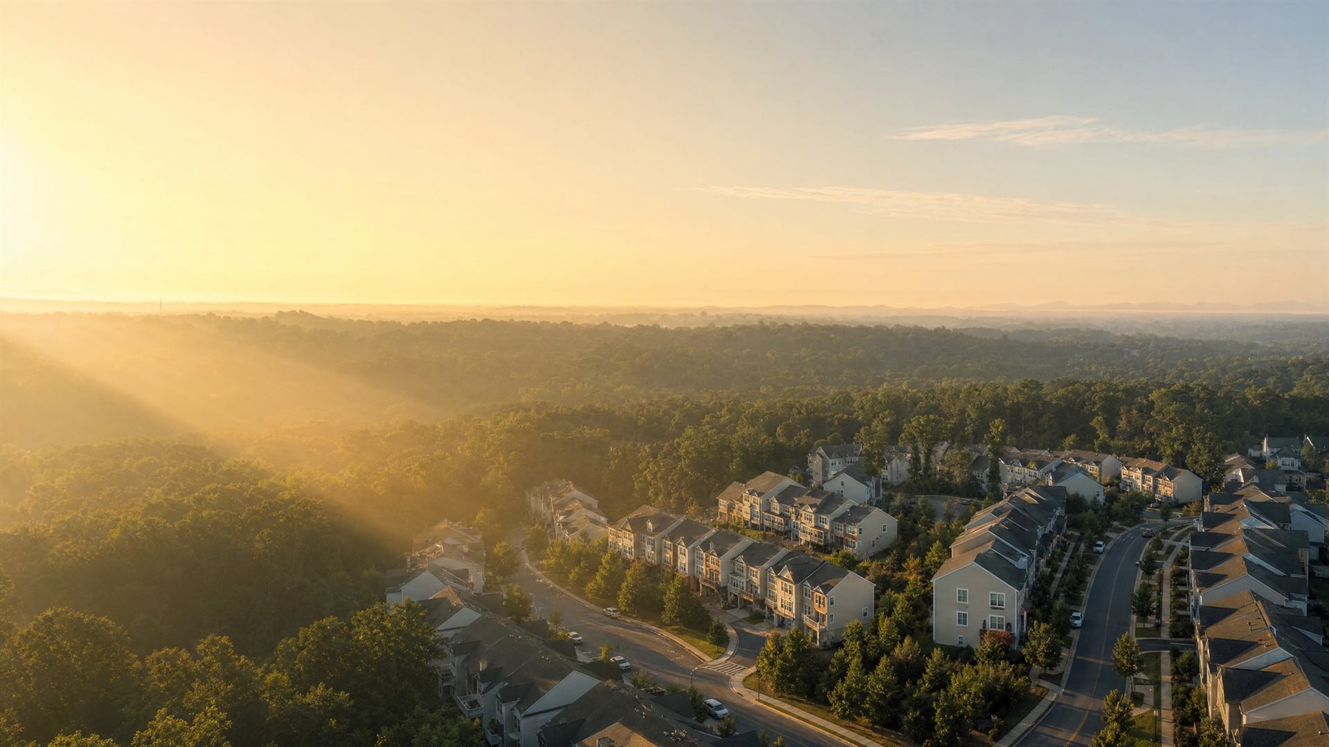 Sunrise over an American townhouse neighbourhood, seen from high above through golden haze.
